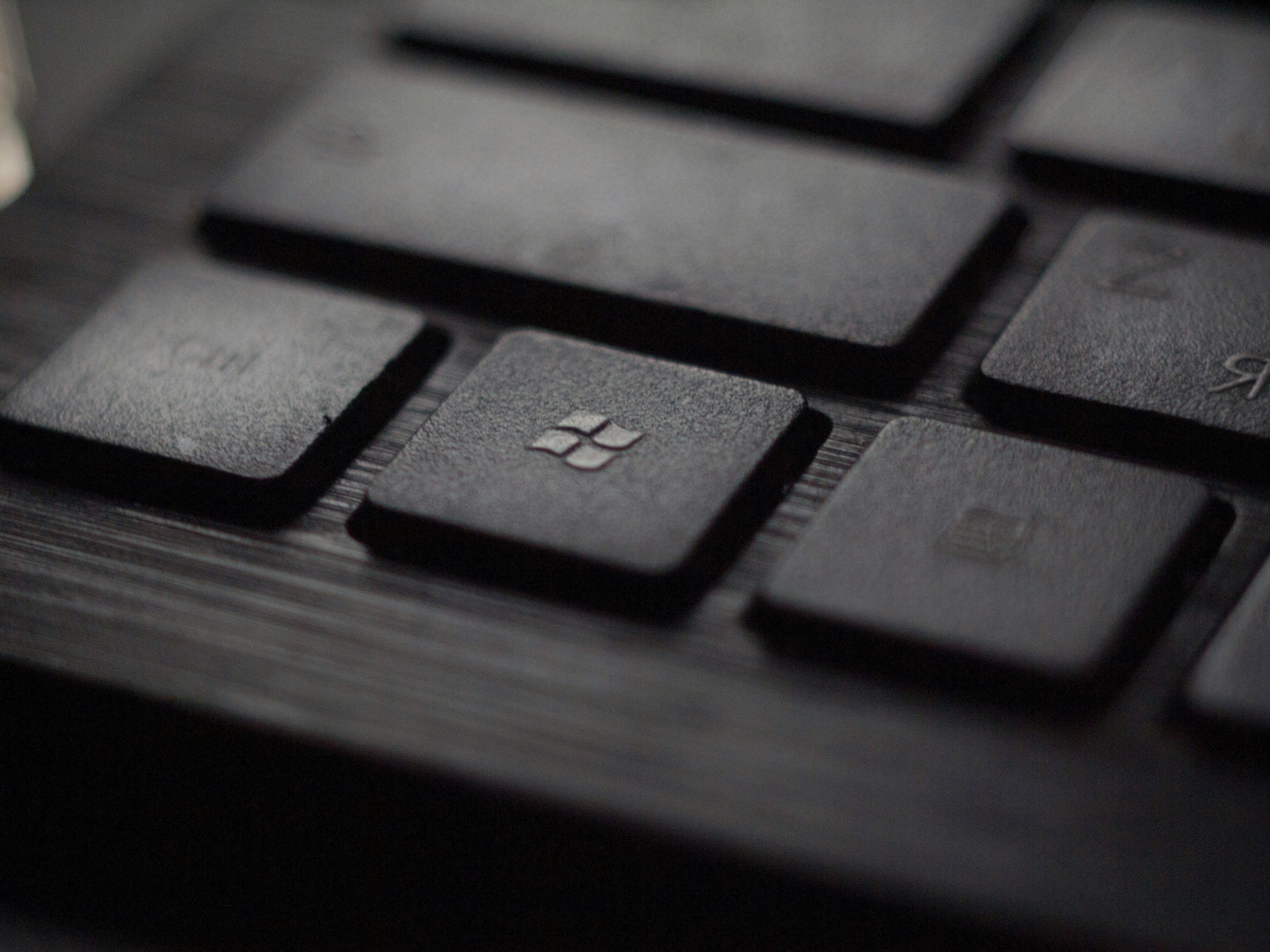 Close-up macro photograph of a black keyboard with the Windows logo key in focus