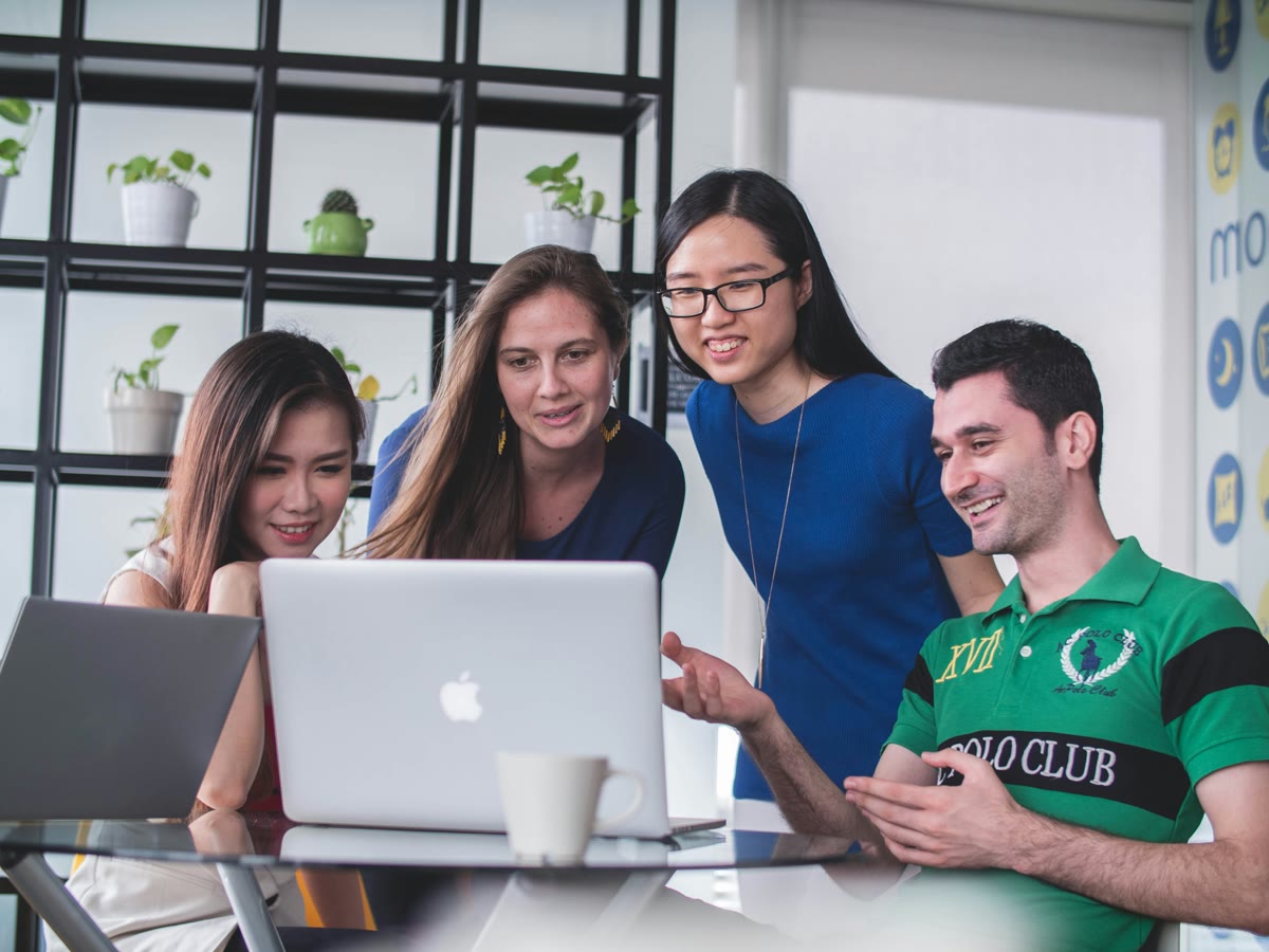 Group of people collaborating around a laptop